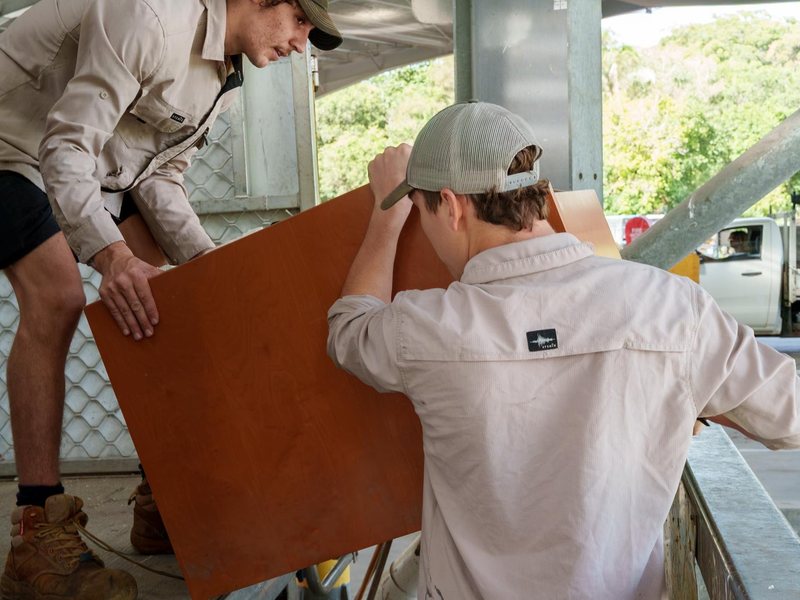 Two Mango crew members carrying a board out to the truck